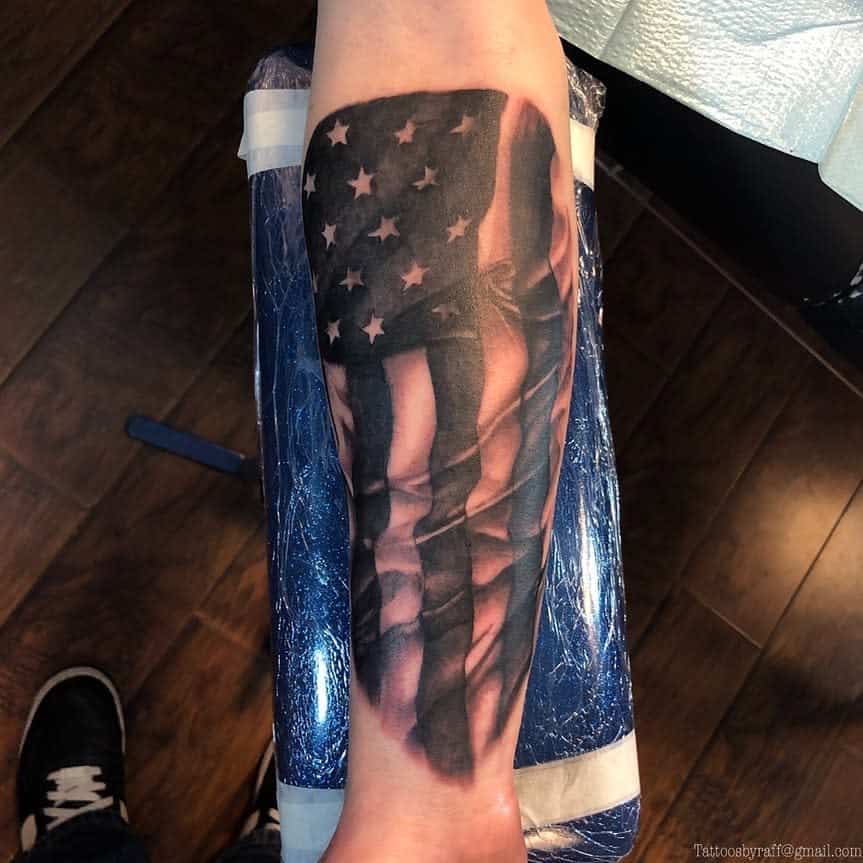 Forearm tattoo of a flowing American flag with stars and stripes
