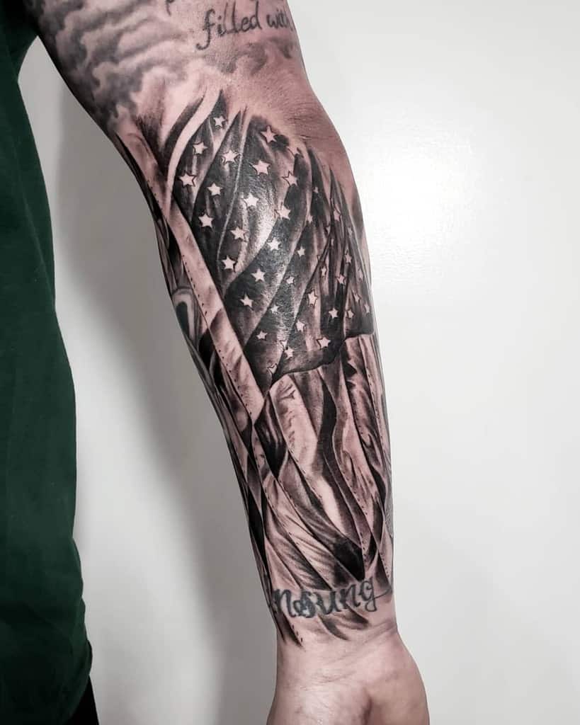 A forearm tattoo of an American flag with a script on the wrist