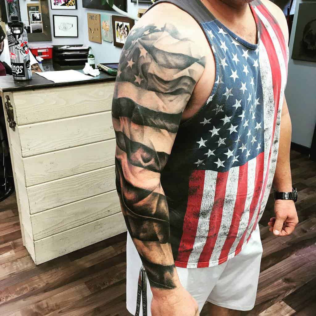 Bold American flag full-sleeve tattoo showcasing dynamic waves in the stars and stripes design, celebrating patriotism with realistic shading