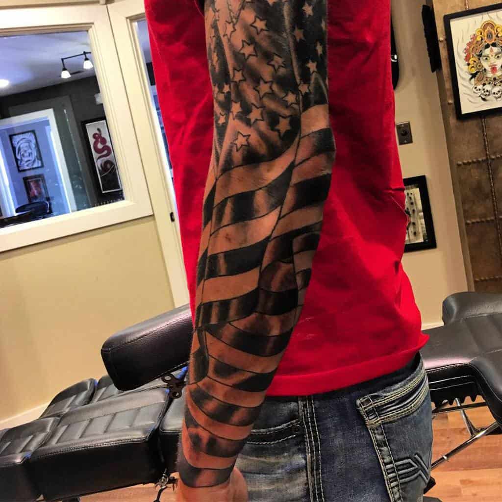 Man with a sleeve tattoo of a stylized American flag on his arm