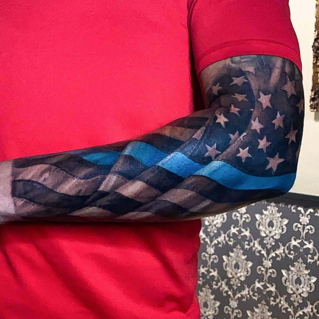 A tattoo of the American flag with a blue line on a man's forearm