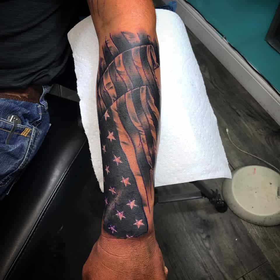 Forearm tattoo of a waving American flag with stars and stripes