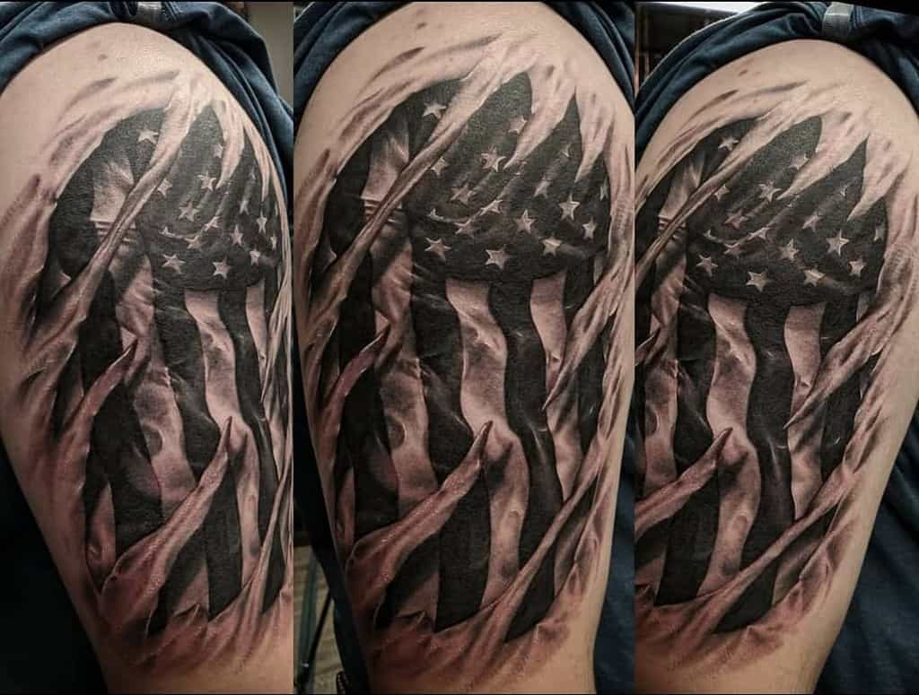 Tattoo of a tattered American flag on an arm, depicted in grayscale