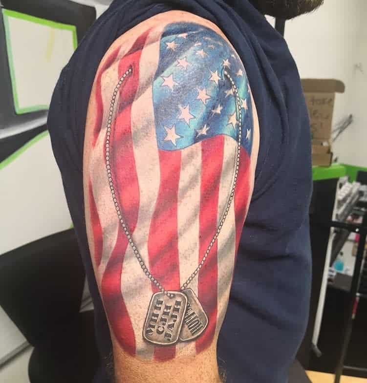 Tattoo of an American flag with a dog tag on a man's upper arm