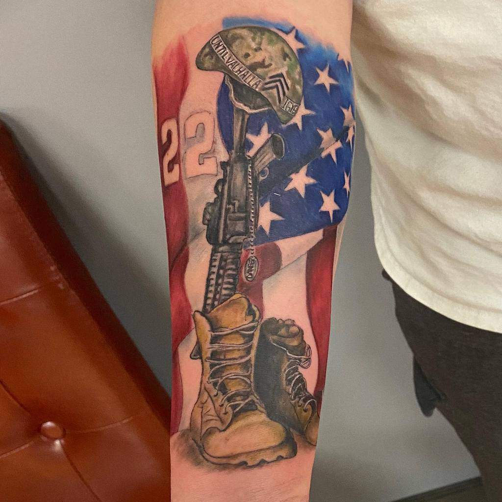Tattoo features a helmet, rifle, boots, and American flag on an arm