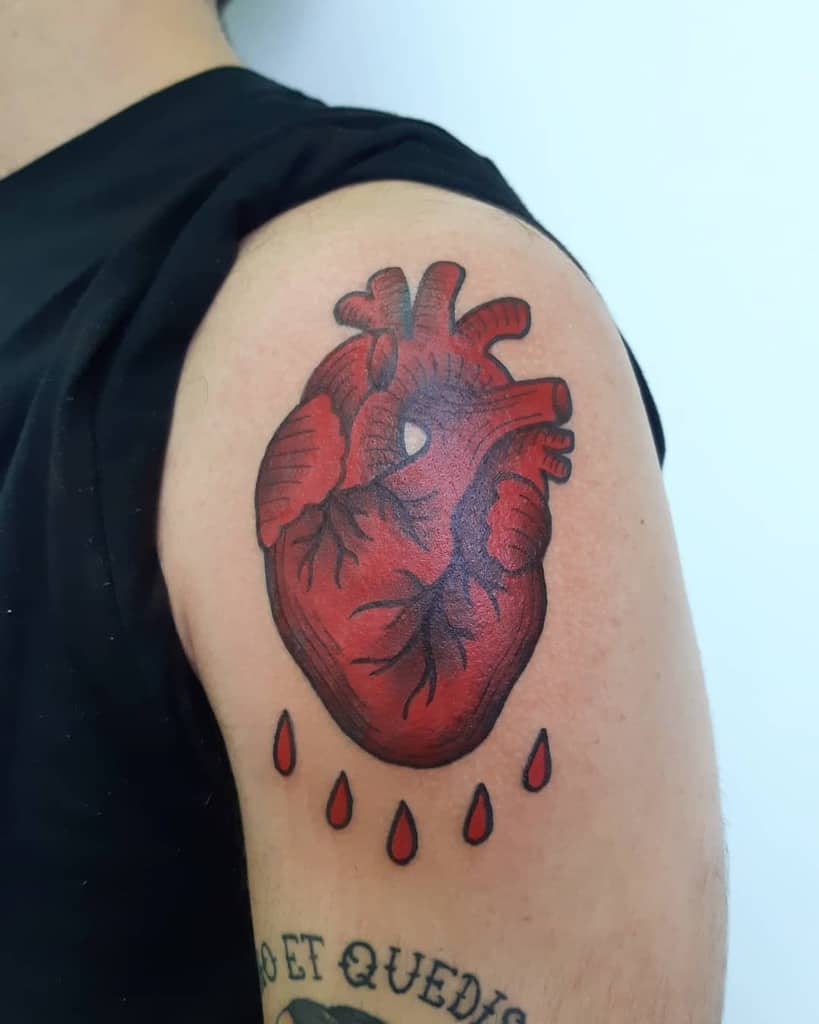 Bold red anatomical heart tattoo with detailed black shading and dripping blood droplets beneath it