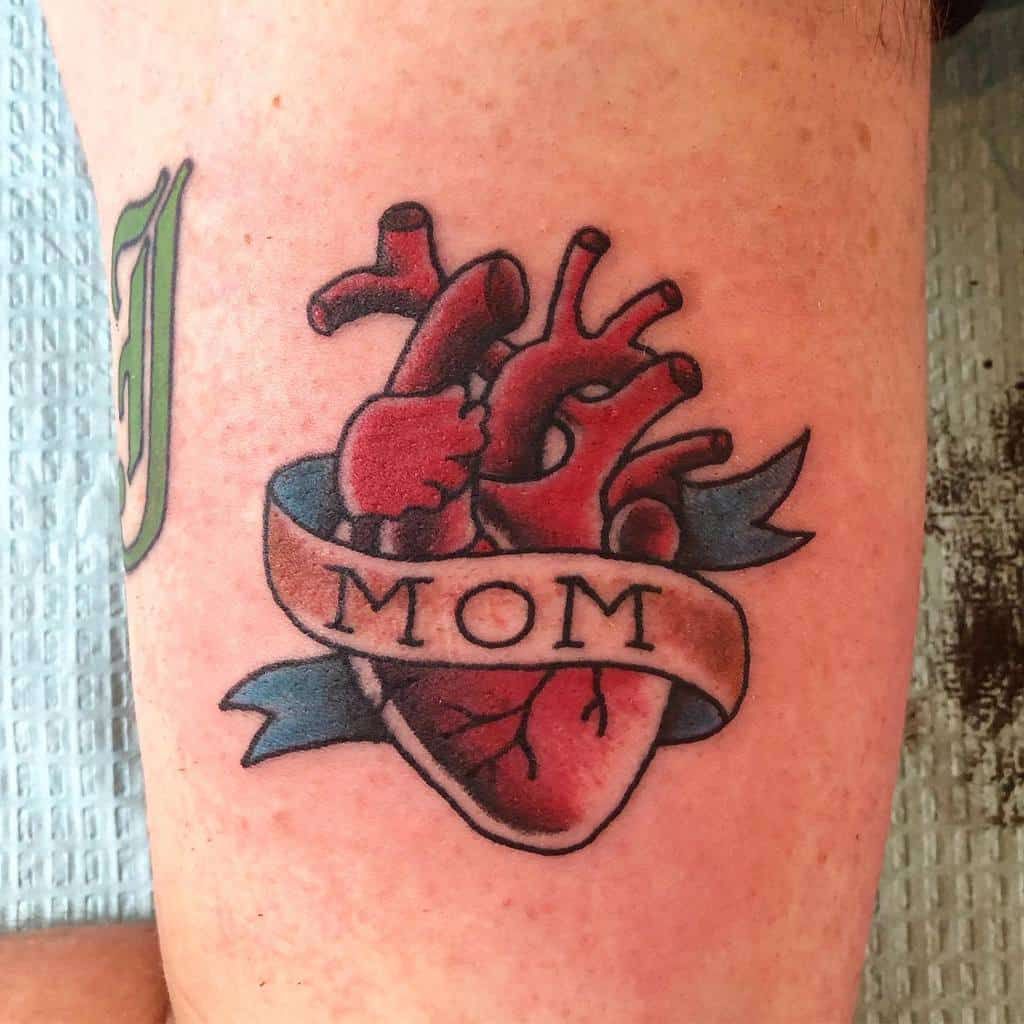 Tattoo of an anatomical heart wrapped in a banner that proudly reads "MOM"
