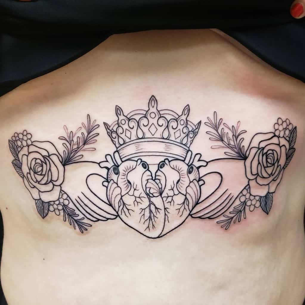 Elegant chest tattoo featuring two anatomical hearts crowned in royalty, framed by roses and intricate floral detailing