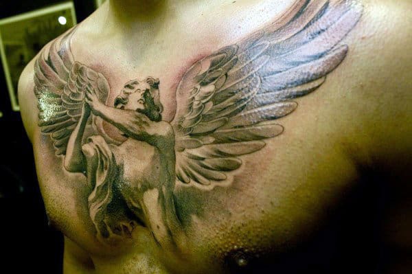 Chest tattoo of an angel with large wings, holding a staff, on a person's torso