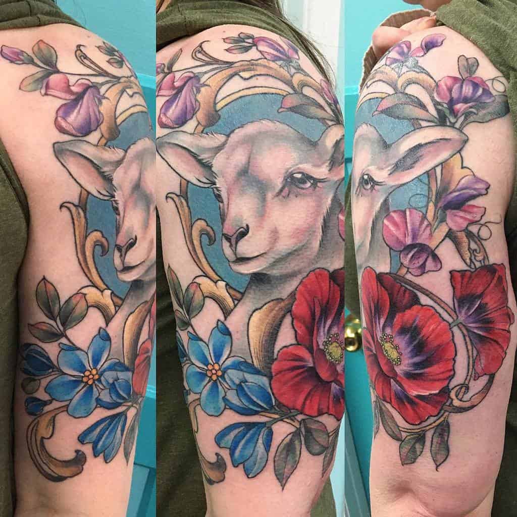 Art Nouveau-style tattoo featuring a serene lamb framed by golden with blue ornaments, vibrant red poppies, blue flowers and flowing vines
