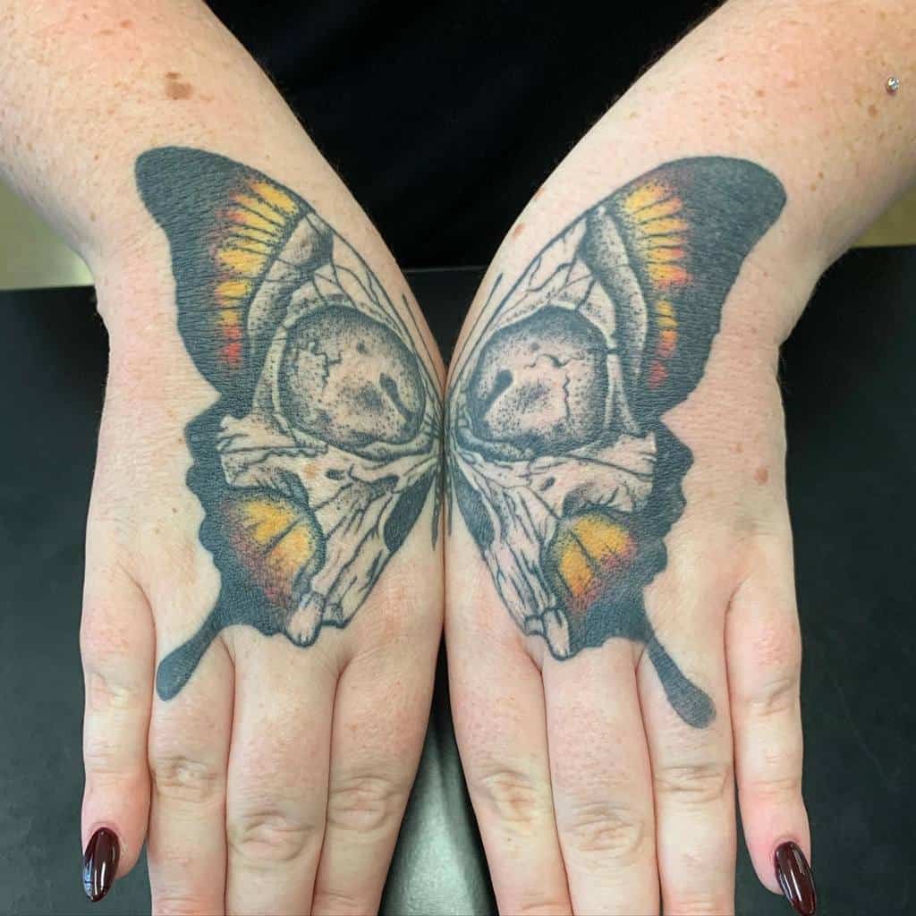 Unique butterfly tattoo featuring a skull design in the center and bold black, orange, and yellow wing details.