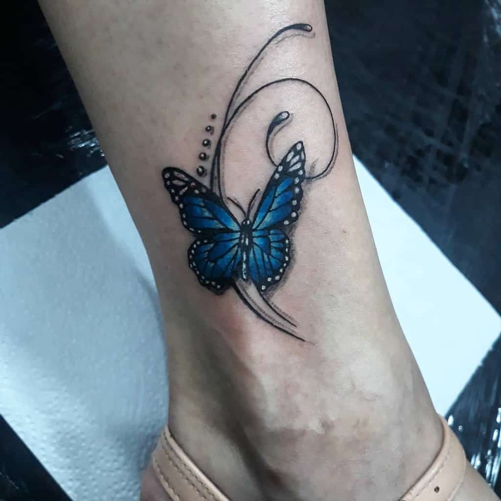 A blue butterfly tattoo with curved lines and dots graces the side of a person's foot