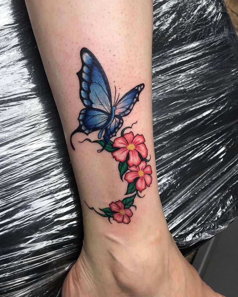 Tattoo of a blue butterfly surrounded by pink flowers on a lower leg