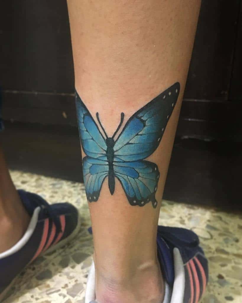 A blue butterfly tattoo graces a person's lower leg, just above the ankle