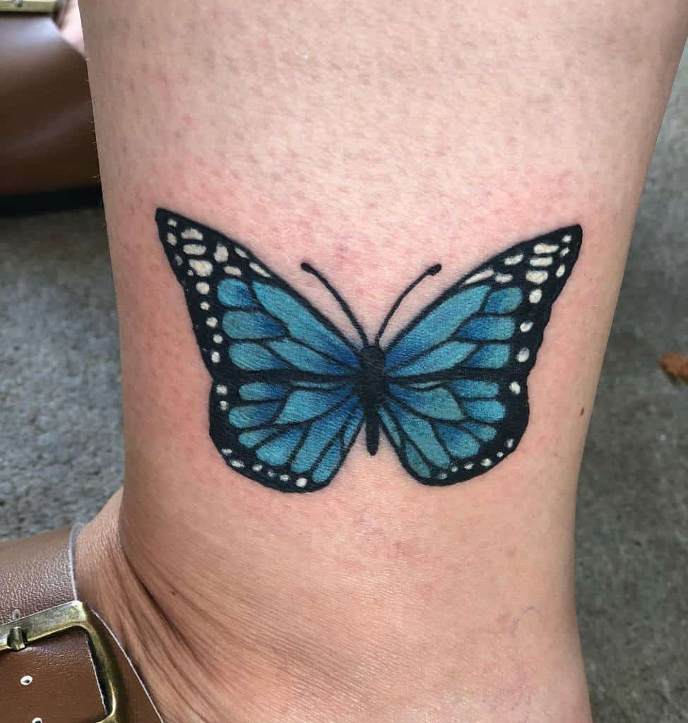 Blue butterfly tattoo on a person's ankle
