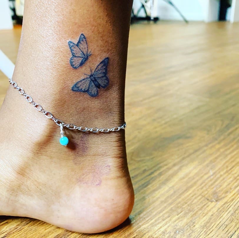 Ankle tattoo of a blue butterfly alongside another butterfly