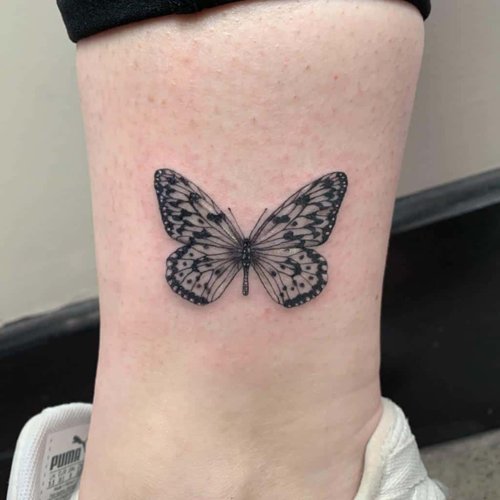 A black and white monarch butterfly tattoo on the ankle