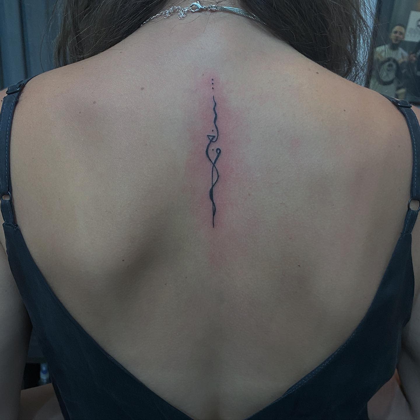 Minimalist line tattoo on the upper back