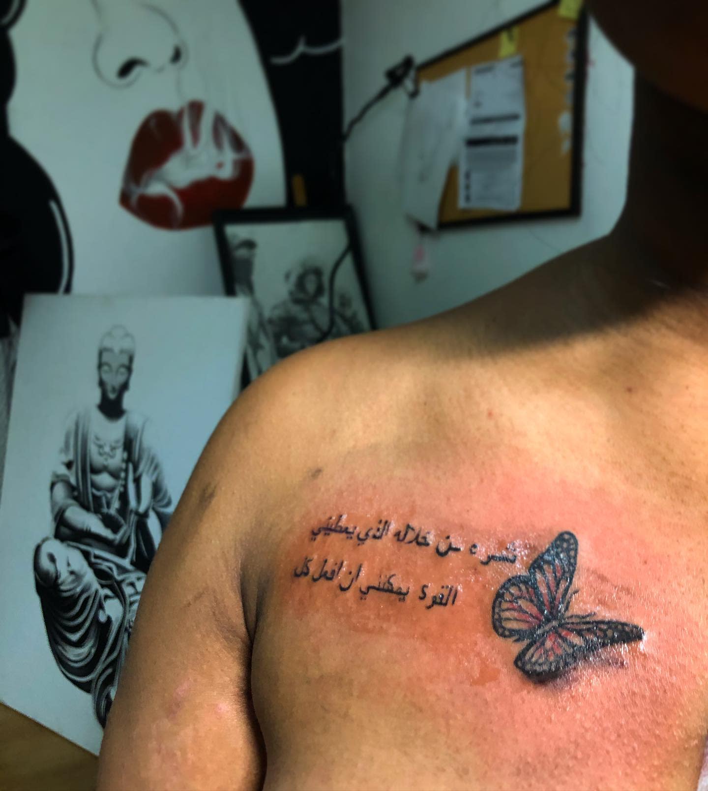 Chest tattoo of a butterfly and Arabic text