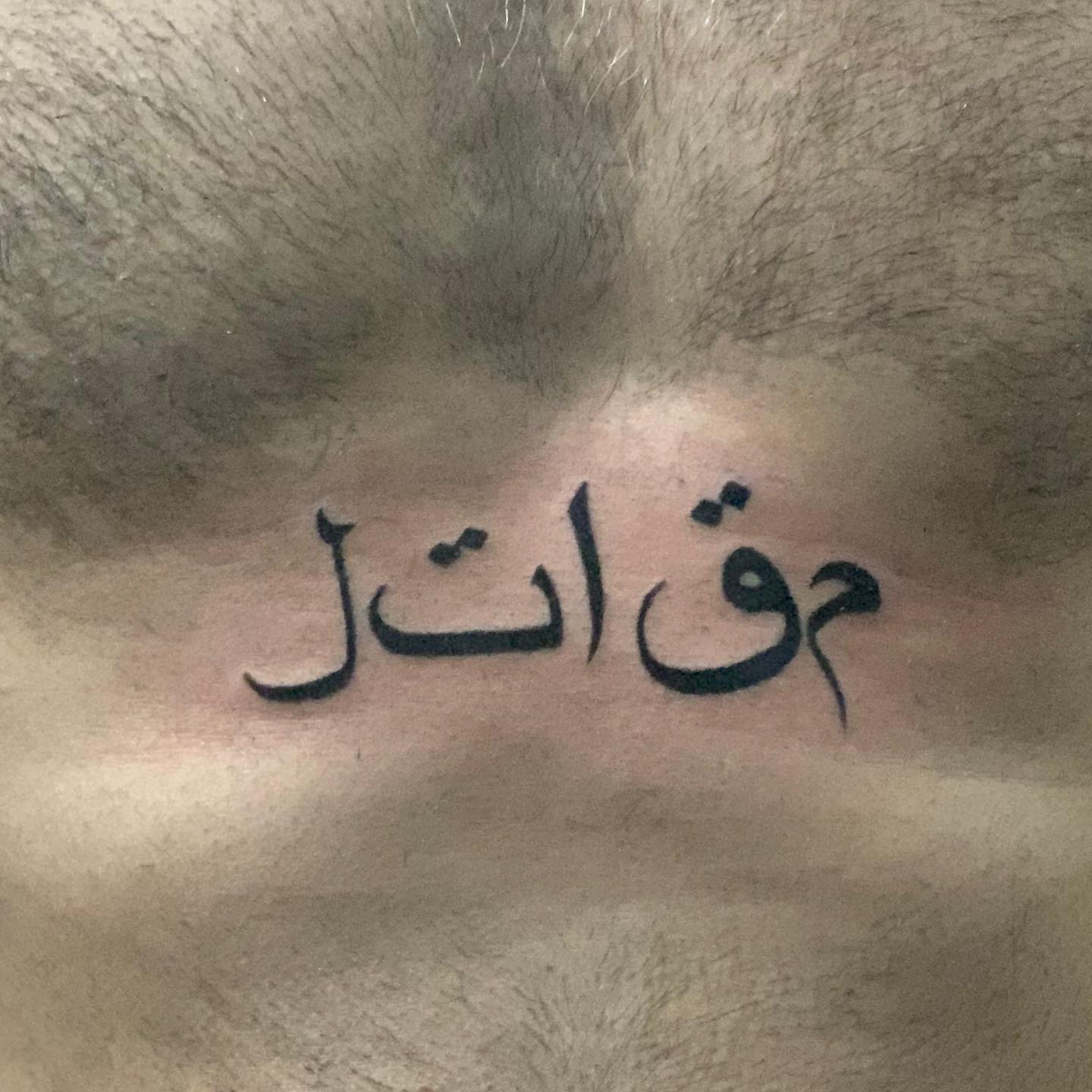 A tattoo with Arabic script on a chest