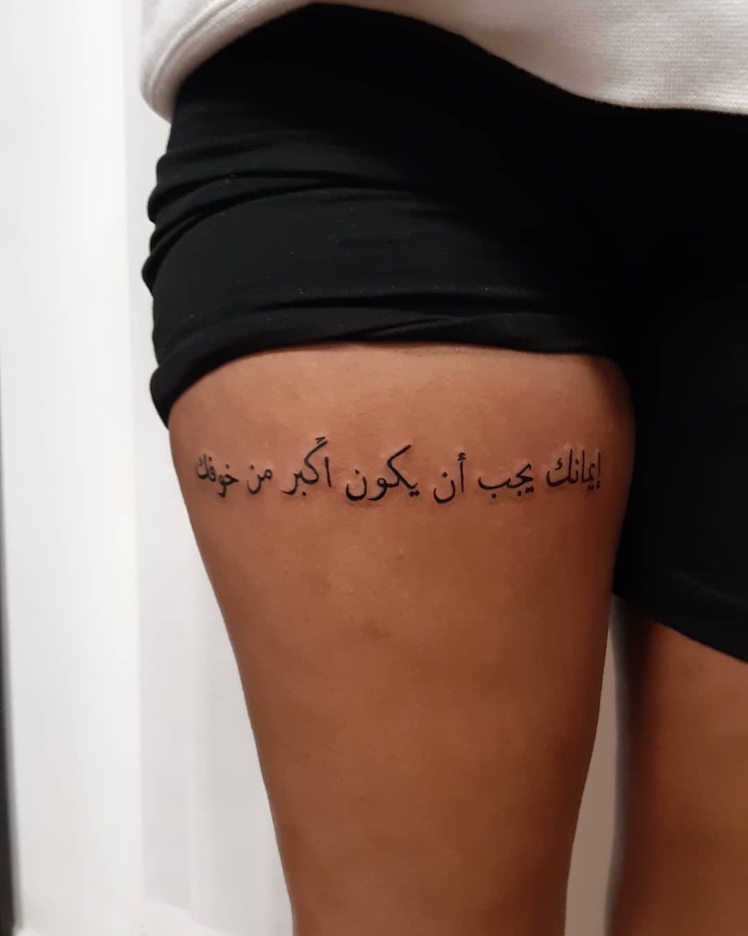 Arabic script tattoo on an upper thigh