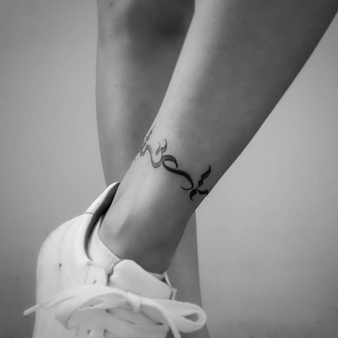 Black tattoo of an Arabic script around an ankle