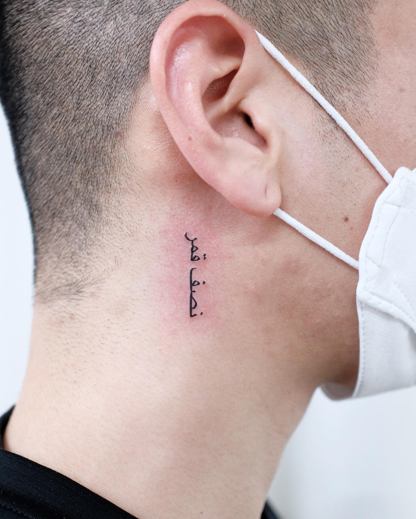 Tattoo in Arabic script behind the ear