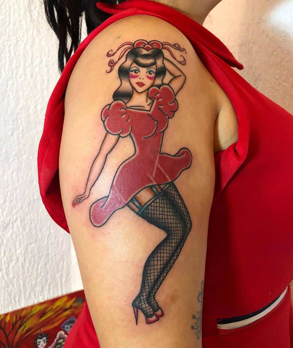 A colorful tattoo on an arm depicting a woman in a red dress and fishnet stockings with a red headband and black hair