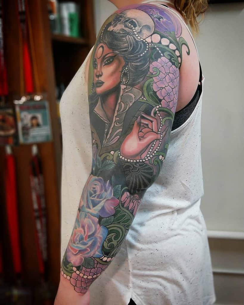 Art Nouveau-style tattoo sleeve featuring a mysterious woman with dark hair, pearls, a skull moon, and intricate floral and ornamental designs