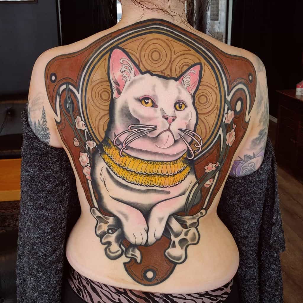 Art Nouveau-style full-back tattoo of a regal white cat with golden eyes, ornate jewelry, floral details, and swirling patterns