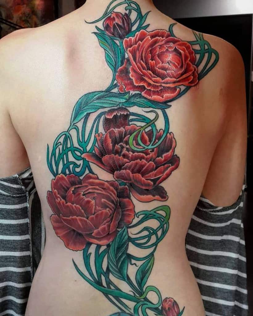 Art Nouveau-inspired tattoo of red peonies with lush green vines flowing elegantly in a detailed, organic design