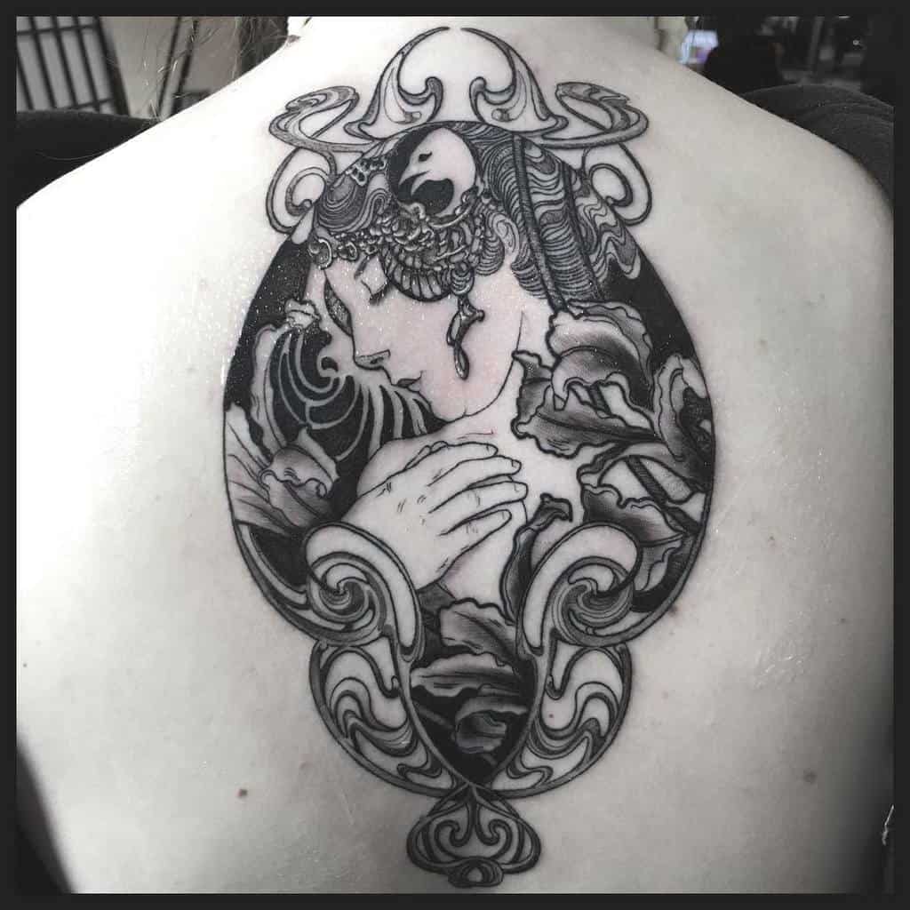 Black and grey Art Nouveau tattoo of an elegant woman with flowing hair, floral details, and ornamental swirls