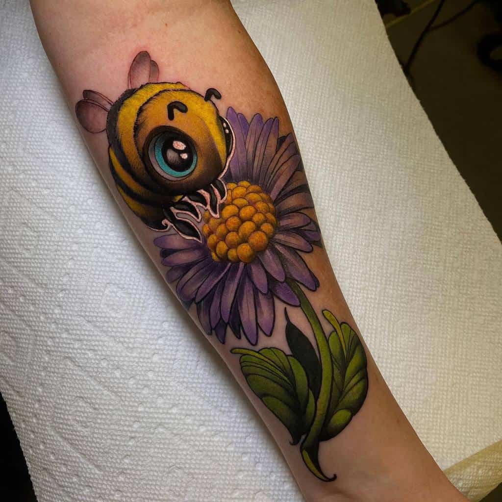 Tattoo of a cute bee with big eyes perched on a purple aster flower on a person's forearm