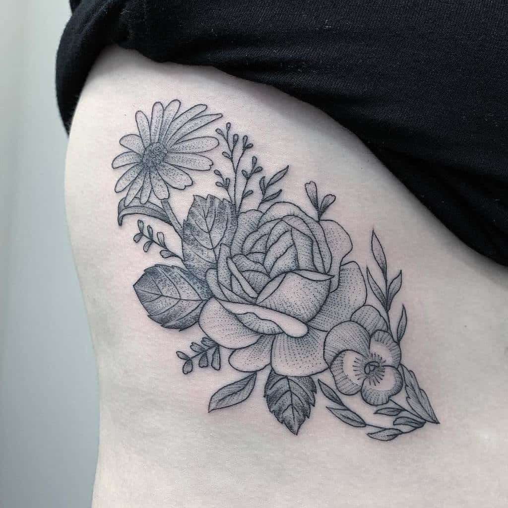Black and white floral tattoo featuring a rose, daisy, aster, and leaves on the side of a torso