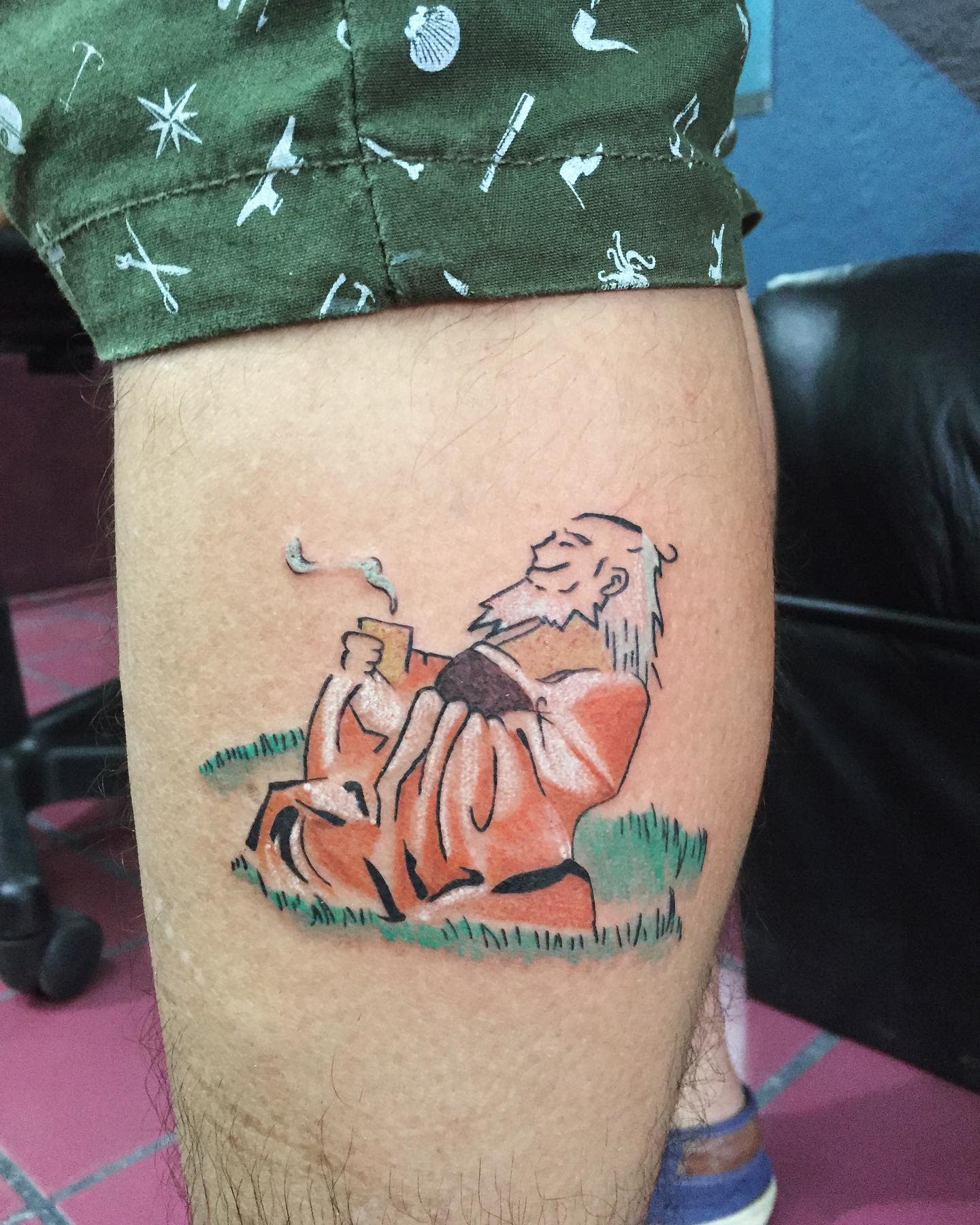Tattoo of Iroh sitting in a grassy field, sipping tea on the calf