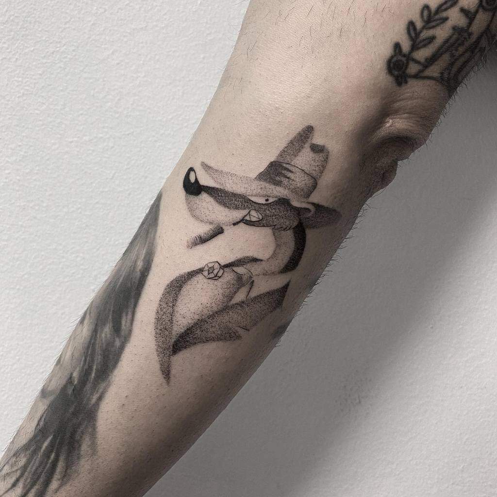 Tattoo of a cartoon character in a hat and cape on an inner forearm, crafted with single needle precision