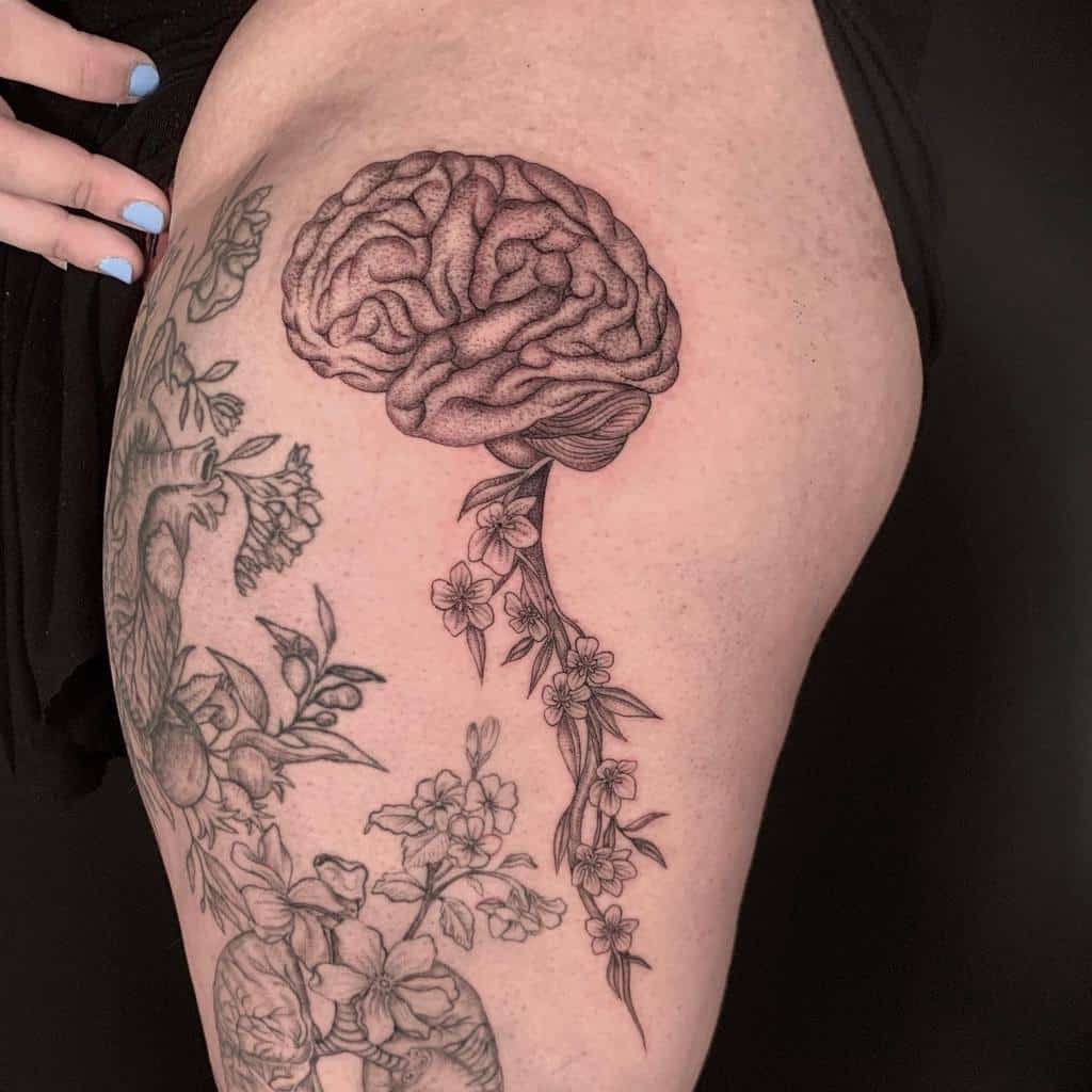Single needle brain and floral tattoo design on an upper thigh with delicate shading