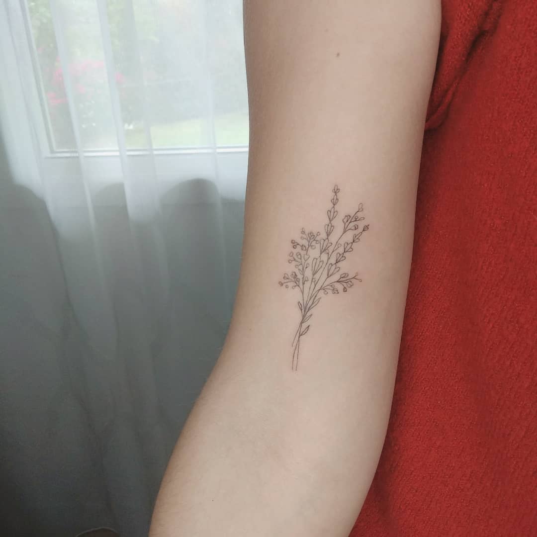 Minimalist baby's breath tattoo on an arm