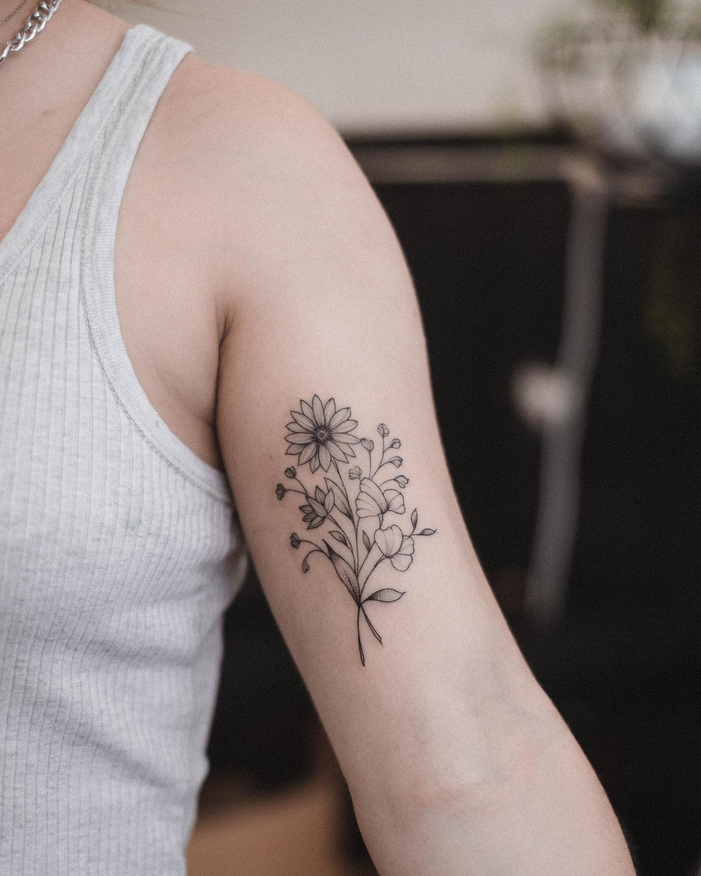 Individual with a baby's breath tattoo on their upper arm