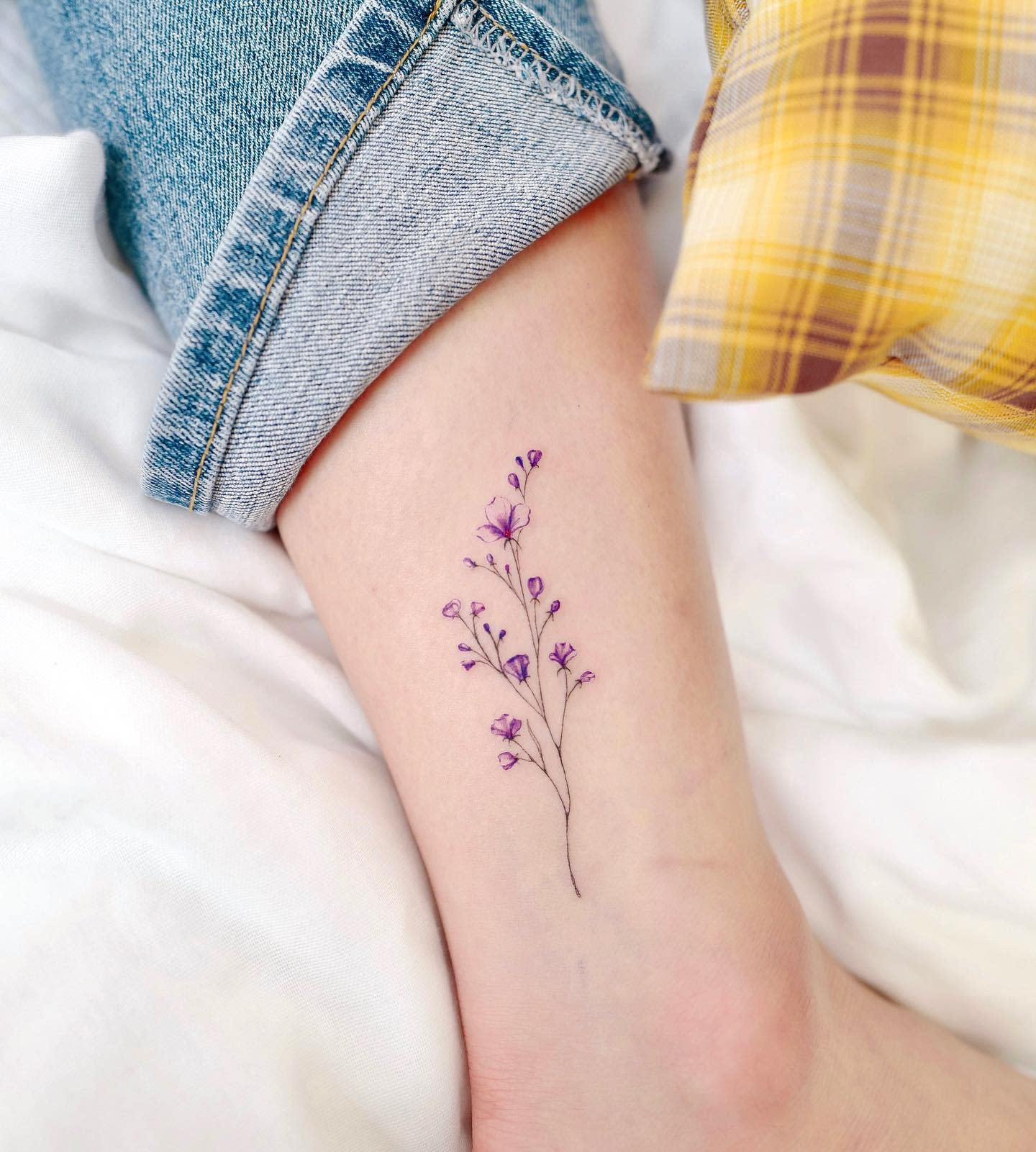 Delicate purple baby's breath tattoo on an ankle