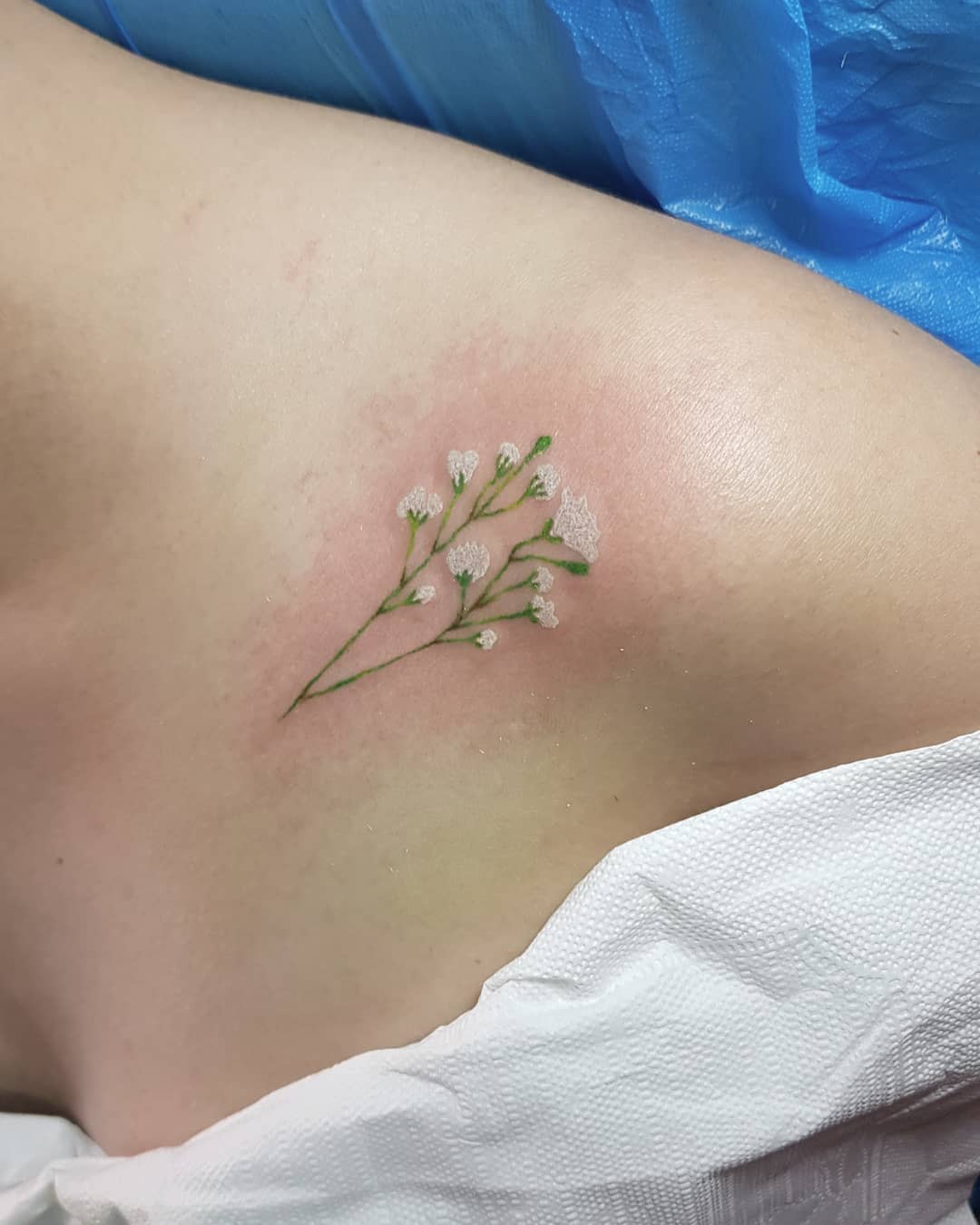 Close-up of a delicate baby's breath flower tattoo on the side of a torso