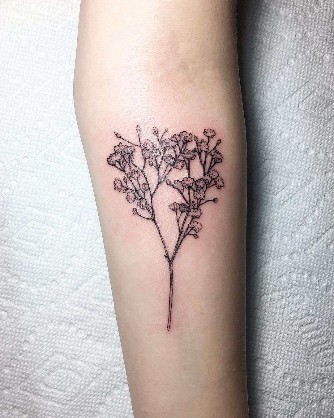 Forearm tattoo of delicate, black ink baby's breath flowers
