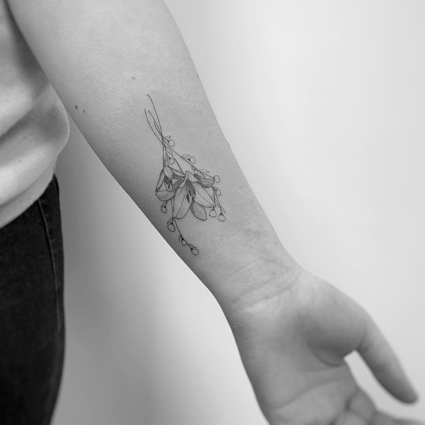 Forearm tattoo of delicate baby's breath and leaves in black and white