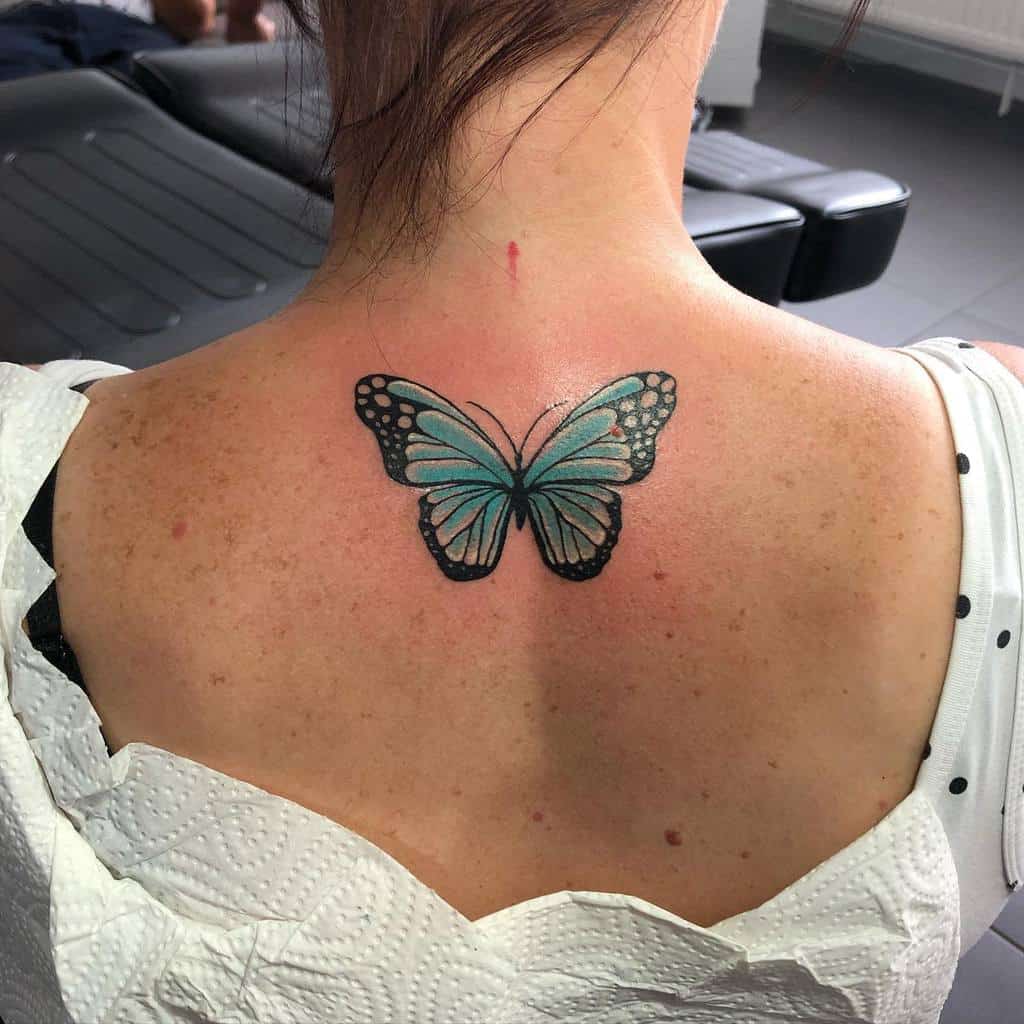 A person with a blue butterfly tattoo on their upper back