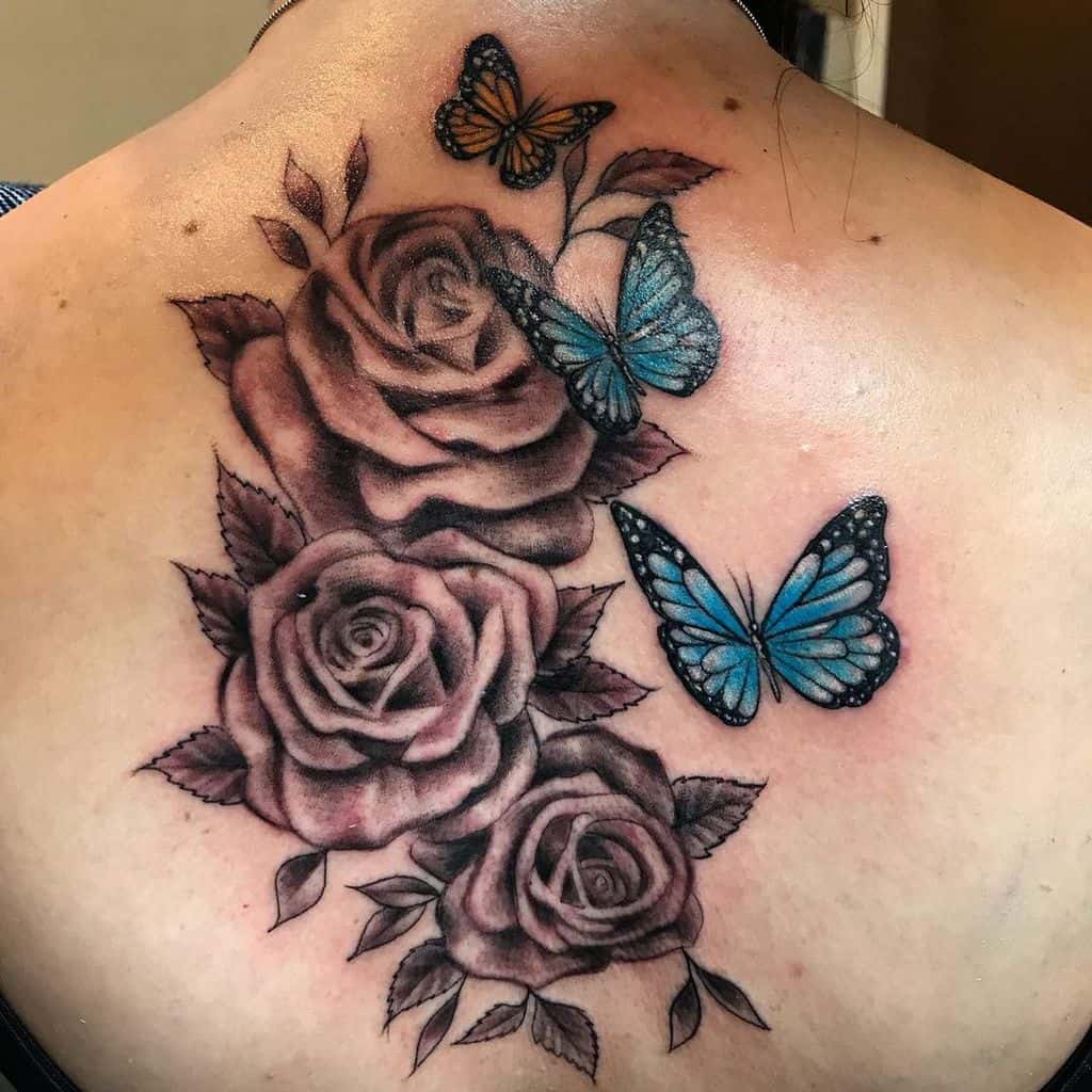 Tattoo of roses and a striking blue butterfly in black and blue ink on a woman's upper back