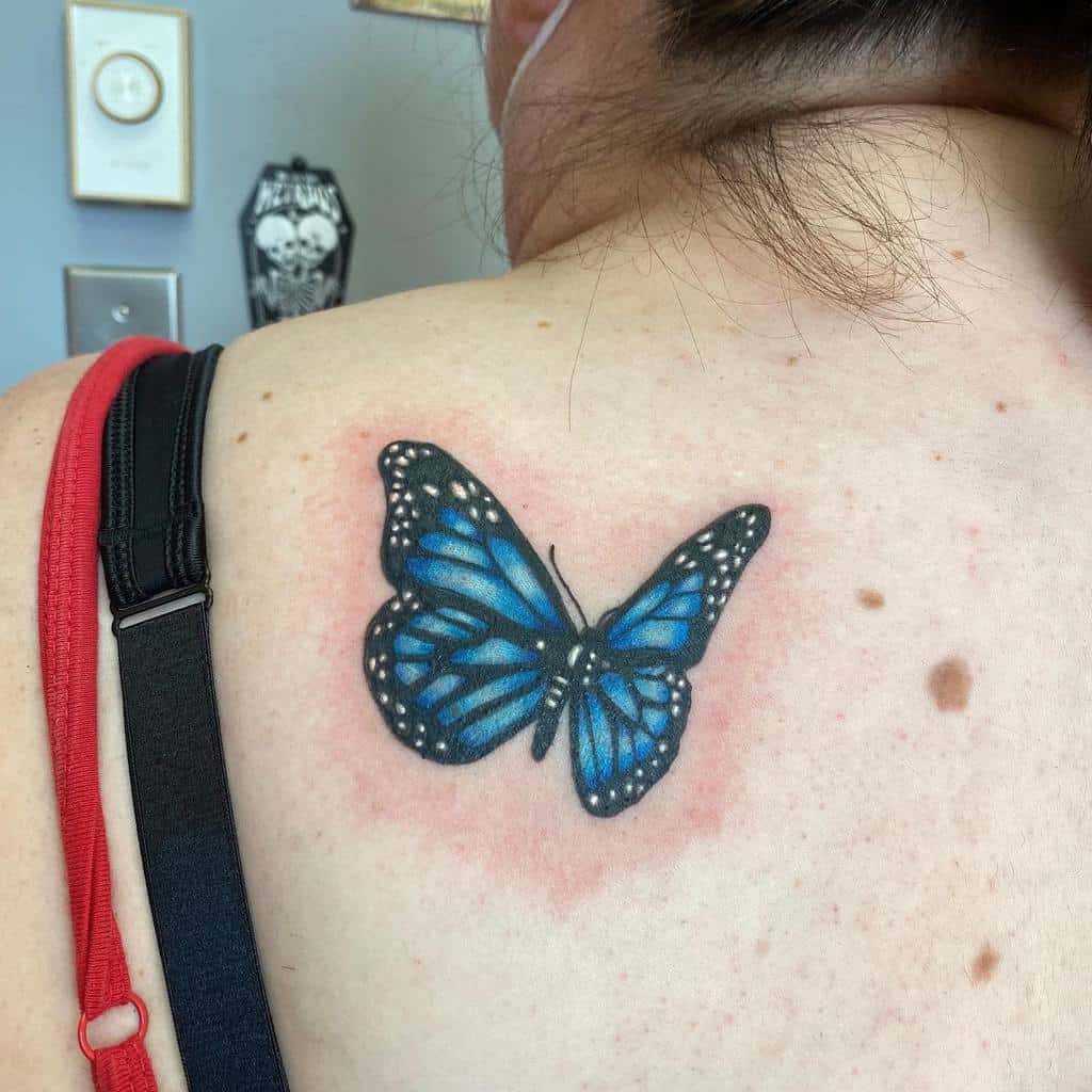 A delicate blue butterfly tattoo graces woman's upper back