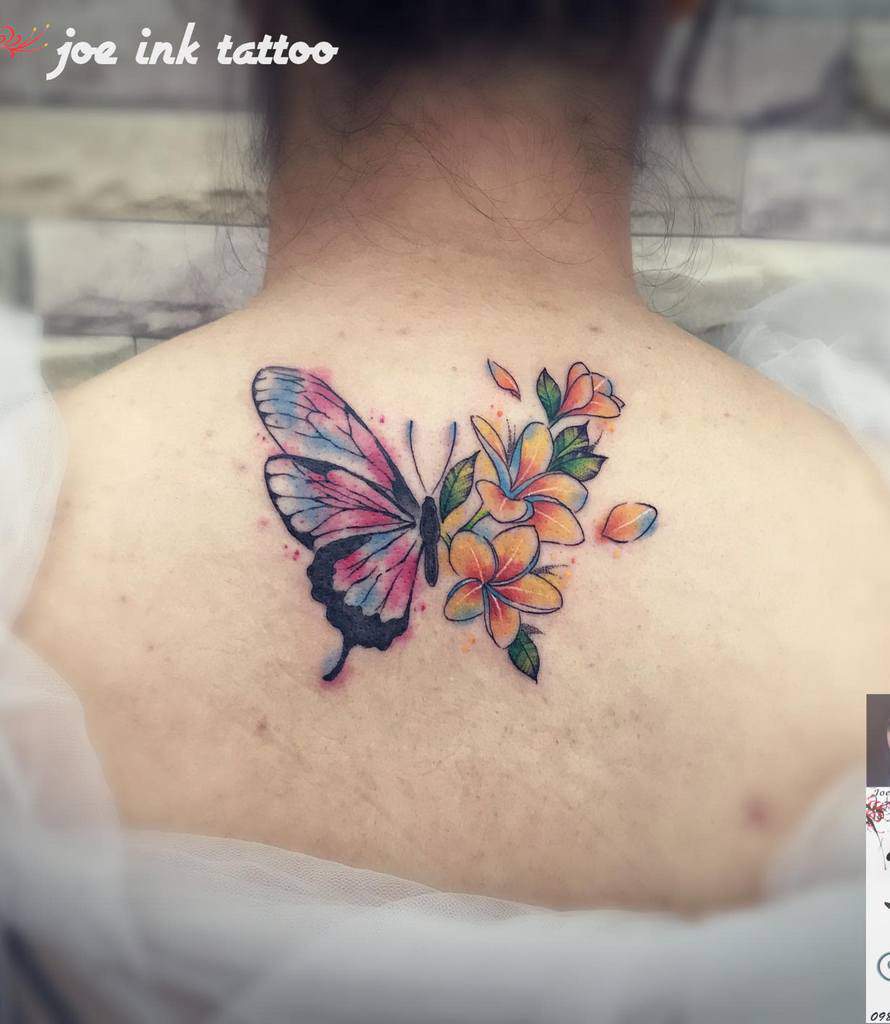 Colored tattoo of a butterfly and flowers on a person's upper back
