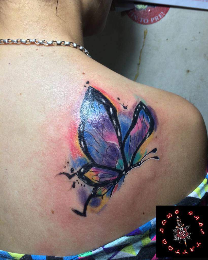 Colorful abstract butterfly tattoo on a person's upper back
