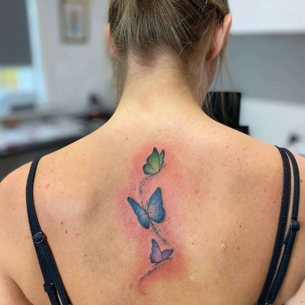 Woman with a colorful butterfly tattoo on her upper back