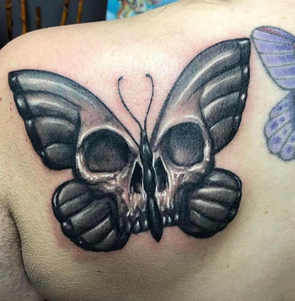 Tattoo of a butterfly with skull designs on its wings on a person's shoulder blade
